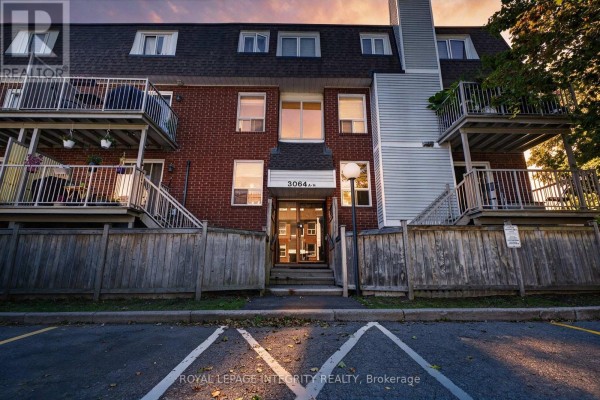 Front exterior of a brick townhouse building with a central entrance and wooden fences. - 31 - 3064a Councillor's Way, Ottawa