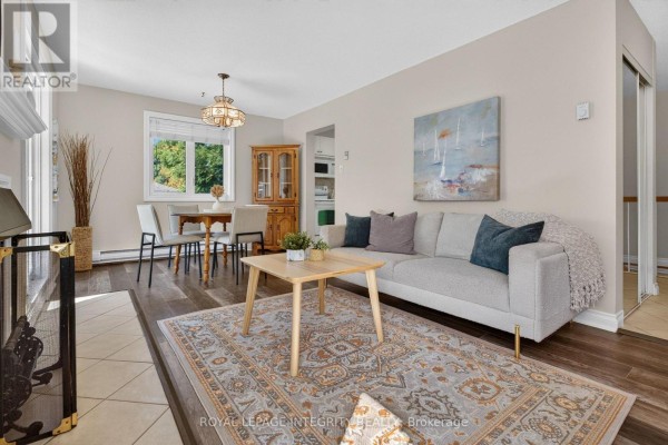 Living and dining area with a light grey sectional sofa, wooden furniture, and a patterned rug. - 31 - 3064a Councillor's Way, Ottawa
