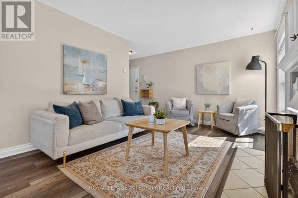 Living room with a light grey sectional sofa, two armchairs, and a coffee table. - 31 - 3064a Councillor's Way, Ottawa