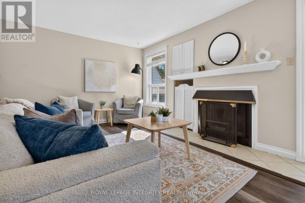 Living room featuring a fireplace, mantle, round mirror, sofa, and armchair. - 31 - 3064a Councillor's Way, Ottawa