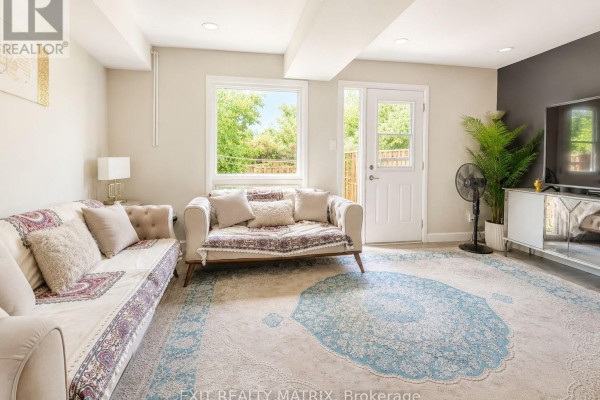 Living area with two sofas, patterned rug, and a door leading outside. - 31 - 67 Angela Private, Ottawa