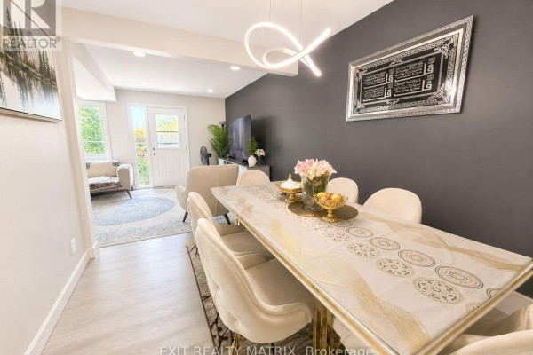Dining area with a table and chairs, next to a living area with a modern light fixture. - 31 - 67 Angela Private, Ottawa