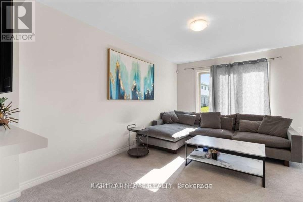 Living room with a grey sectional sofa, coffee table, and abstract wall art. - 31 - 7945 Oldfield Road, Niagara Falls