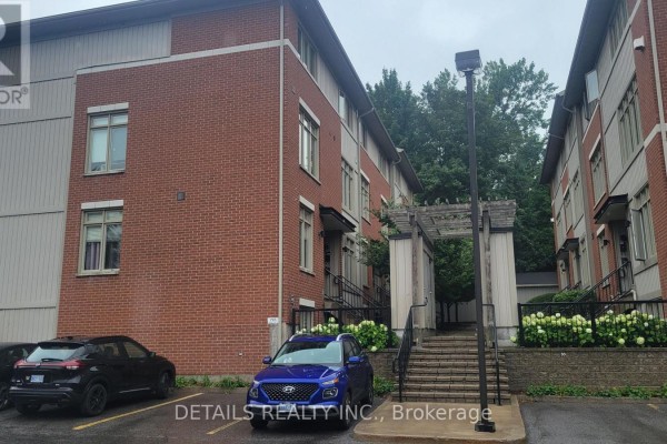 Exterior view of red brick townhouses with cars parked in front and a covered walkway. - 1 - 795 Montreal Road, Ottawa