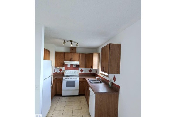 U-shaped kitchen with oak cabinets, white appliances, and tiled flooring. - #31 10909 106 St Nw Nw, Edmonton