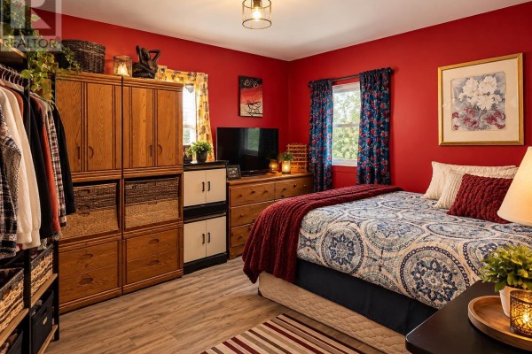 Bedroom with red walls, a queen-size bed, wooden wardrobe, dresser, and patterned curtains. - 31-15 Fish Hatchery Rd, Sault Ste  Marie