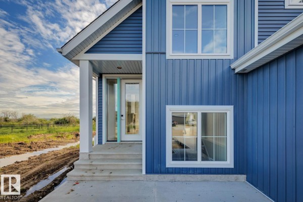 Front view of a blue house under construction with Tyvek wrap and a large propane tank. - #31 3410 Ste Anne Trail, Rural Lac Ste  Anne County