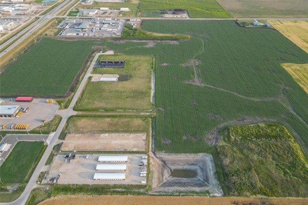 Aerial view of agricultural land, showing buildings, a pond, and surrounding fields. - 31 40 North Gate Drive, Steinbach
