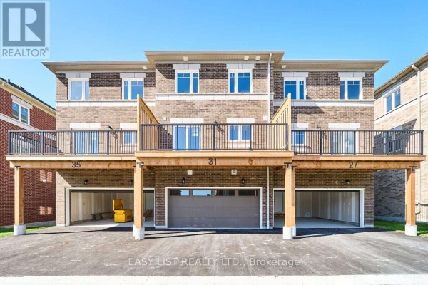 Rear exterior of townhouses with garages, decks, and balconies facing a paved driveway. - 31 Addyman Crescent, Clarington
