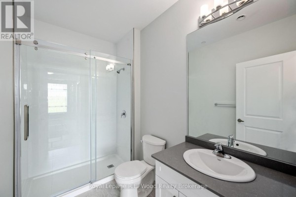 Bathroom with a glass-enclosed shower, white toilet, vanity with grey countertop, and a large mirror. - 31 Anne Street, Aylmer