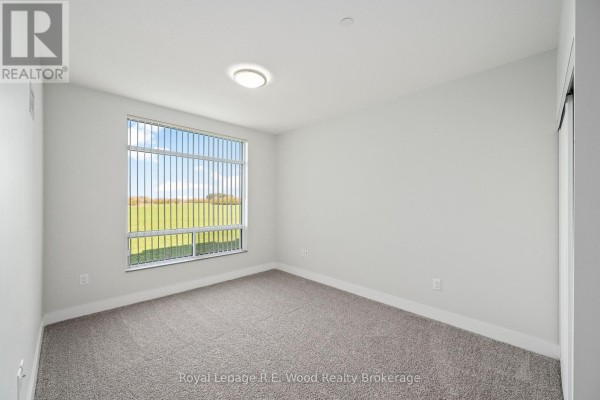 Empty bedroom with grey carpet, white walls, and a large window with a view of a green field. - 31 Anne Street, Aylmer