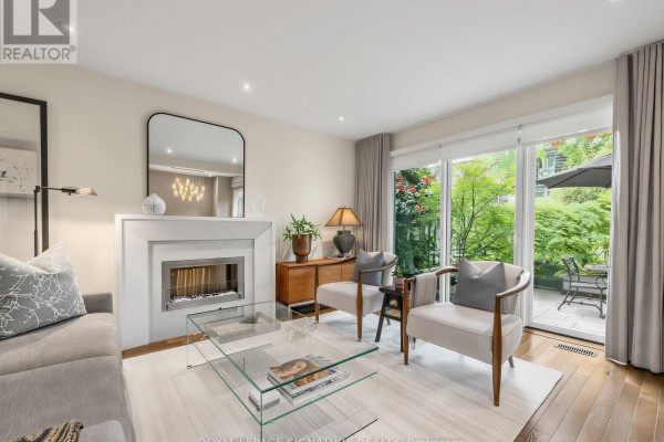 Living room with a grey sofa, fireplace, glass coffee table, and large window. - 31 Anvil Millway, Toronto