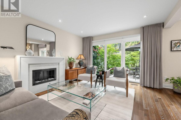 Living room features a fireplace, seating area, and a glass sliding door leading to a patio. - 31 Anvil Millway, Toronto