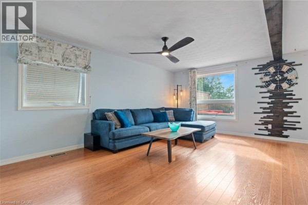 Living room with a large blue sectional sofa, coffee table, and hardwood floors. - 31 Beckett Boulevard, Tillsonburg