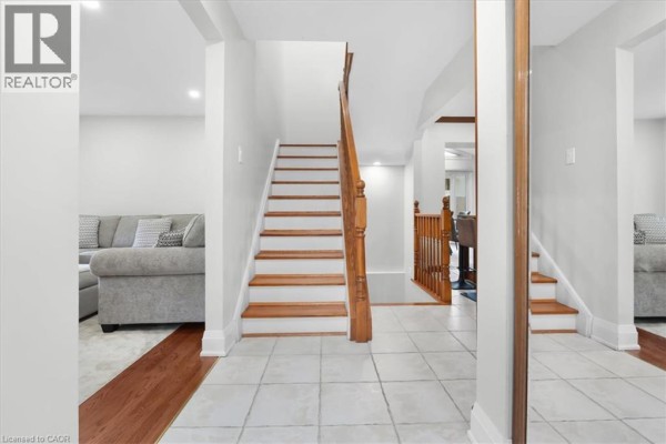 Hallway with a staircase, tiled floor, hardwood floors, and mirrored closets. - 31 Berrisfield Crescent, Hamilton