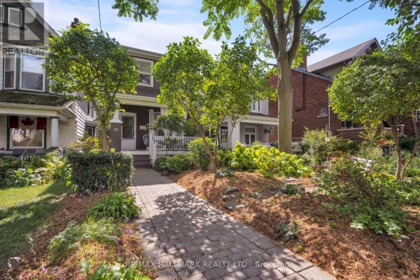 Street view of a detached house with a paved walkway and manicured garden. - 31 Cassels Avenue, Toronto