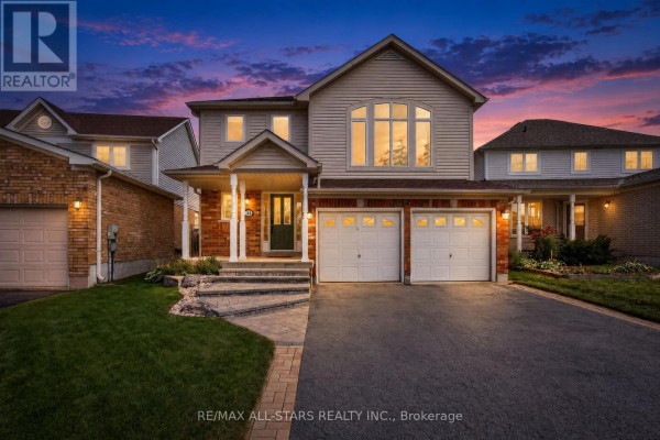 Front exterior of a two-story beige and brick house with a double garage at twilight. - 31 Country Lane, Barrie