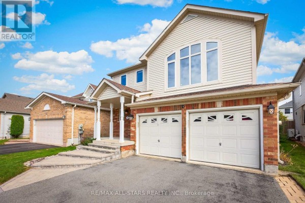 Front exterior of a two-story beige and brick house featuring a double garage. - 31 Country Lane, Barrie