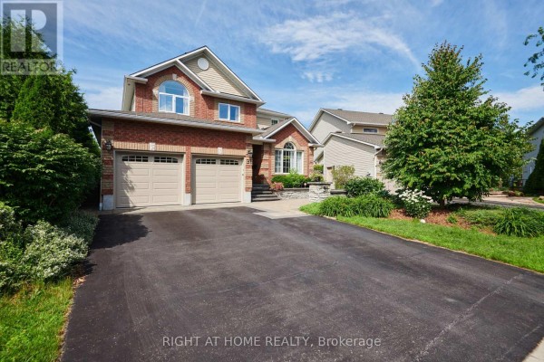 Front view of a brick house with a paved driveway and lush green hedges. - 31 Forillon Crescent, Ottawa