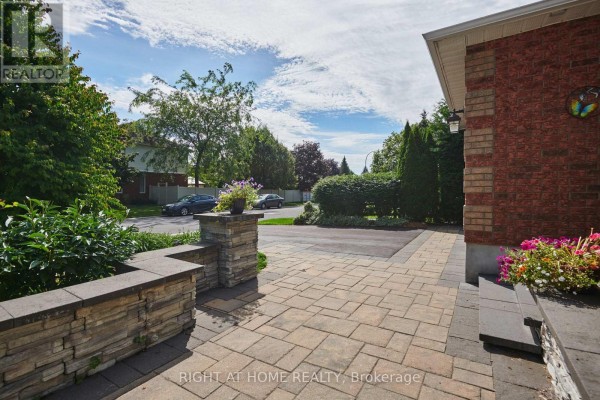 View of the paved driveway and entrance area with stone planter boxes and flowers. - 31 Forillon Crescent, Ottawa