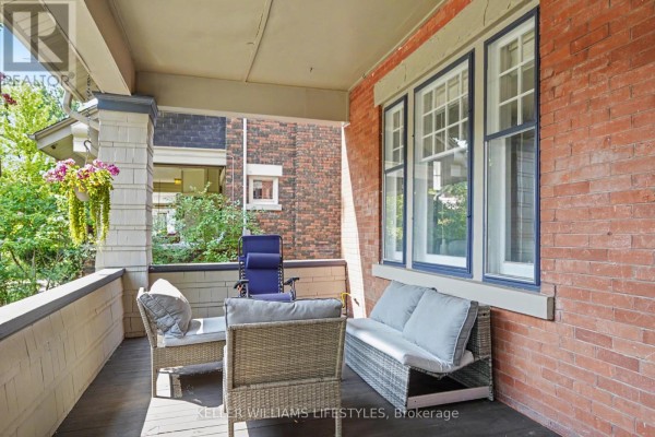 View from the front porch showing brick exterior walls, large windows with blue trim, and outdoor furniture. - 31 Gerrard Street, London South