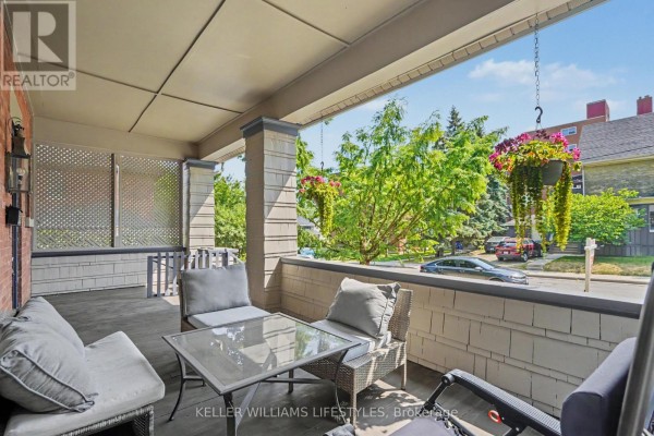 View from the covered front porch overlooking a residential street with mature trees and hanging flower baskets. - 31 Gerrard Street, London South