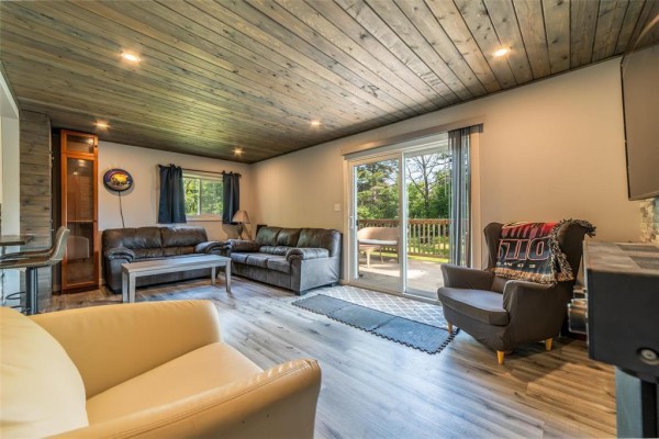 Living room with two sofas, an armchair, and a sliding glass door leading to the outdoor deck. - 31 Gimli Road, Dunnottar