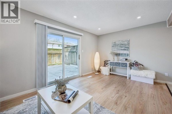 Living room featuring a white sofa, coffee table, and sliding glass doors revealing a patio and fence. - 31 Greengate Road Unit# 239, Guelph