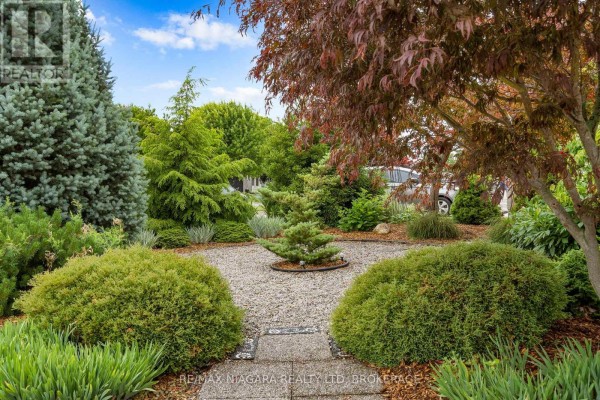 Manicured garden with ornamental trees, shrubs, and gravel pathways. - 31 Hillcrest Road, Port Colborne