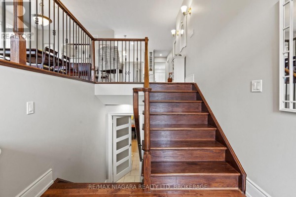 Interior view of a staircase with dark wood treads and banisters leading upstairs. - 31 Hillcrest Road, Port Colborne