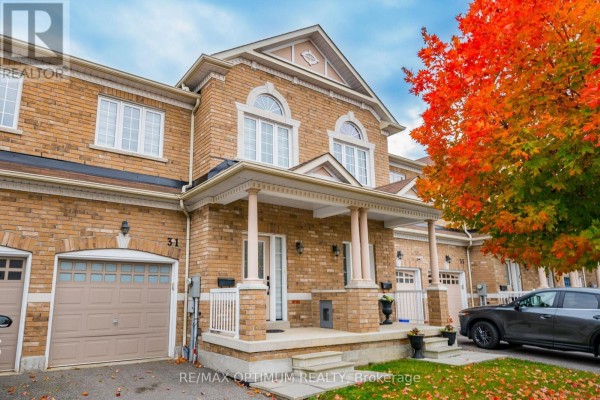 Close-up of the brick townhouse exterior showing the address number 31, a covered porch with columns, and an attached garage. - 31 Keywood Street, Ajax