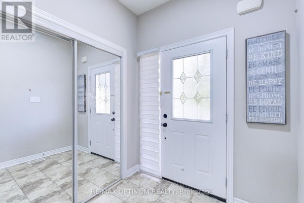 Interior entryway with a front door featuring a diamond-shaped glass insert and a large mirrored closet door. - 31 Keywood Street, Ajax