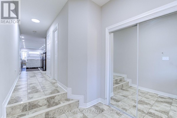 Hallway inside the townhouse showing a tiled floor with stairs leading up, a mirrored closet, and doorways to other rooms. - 31 Keywood Street, Ajax