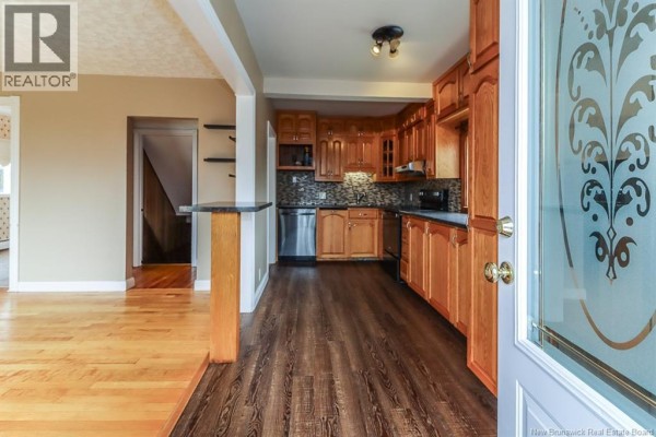View from doorway into open-concept kitchen and living area with wood floors. - 31 Kilburn Avenue, Saint John