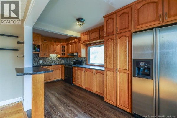 Kitchen with light wood cabinets, dark countertops, and stainless steel refrigerator. - 31 Kilburn Avenue, Saint John
