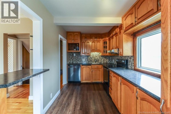 Kitchen with wood cabinets, black appliances, and a window over the sink. - 31 Kilburn Avenue, Saint John