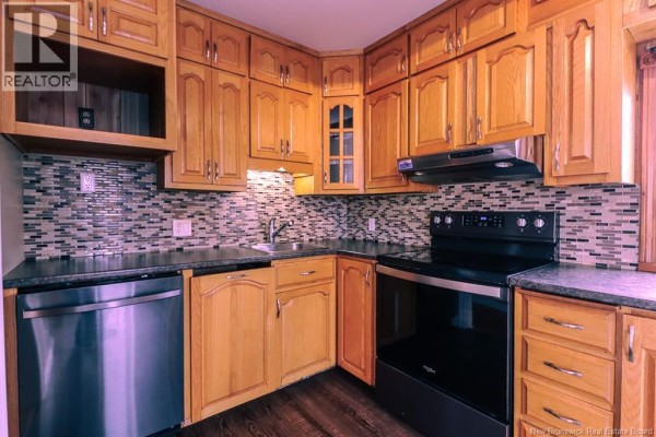 Close-up of kitchen counter with sink, stove, and backsplash tiling. - 31 Kilburn Avenue, Saint John