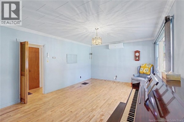 Living room with light blue walls, wood floors, a piano, and an armchair with a yellow blanket. - 31 Mcleod Avenue, Chipman