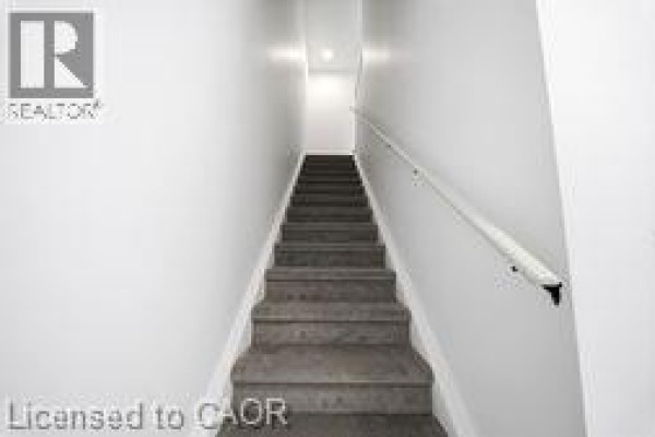 Living room and kitchen area with light wood floors, white walls, and a breakfast bar. - 31 Mill Street Unit# 12, Kitchener