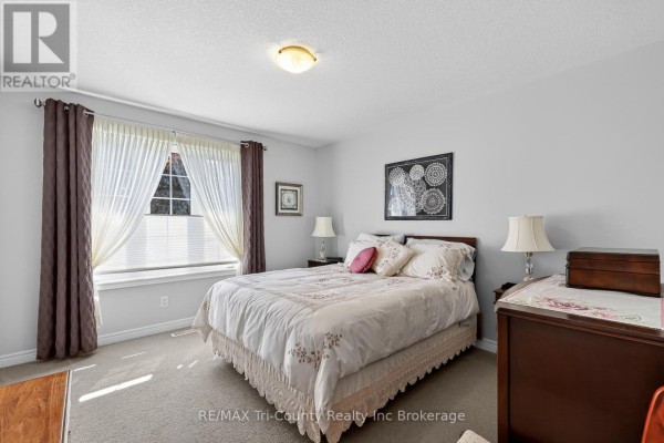 Bedroom with a queen-size bed, dark wood dresser, and large window with drapes. - 31 Morning Glory Drive, Tillsonburg