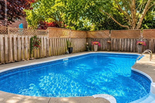 In-ground swimming pool with a wooden privacy fence and landscaping in the backyard. - 31 Mulholland Drive, Vaughan