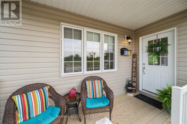 Porch area with wicker chairs, colorful cushions, and welcome sign. - 31 Reynolds Drive, Ramara