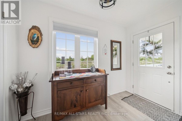 Entryway with a wooden console table, large windows, and front door. - 31 Reynolds Drive, Ramara