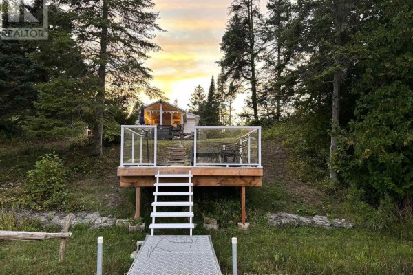 Waterfront cottage with deck and dock at sunset, viewed from the water. - 31 Sog-je-wa-sa Drive, Native Leased Lands