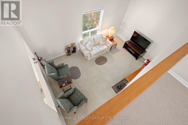 Vaulted ceiling living room with sofa, armchairs, TV, and fireplace - 31 Tamblyn Crescent Ottawa