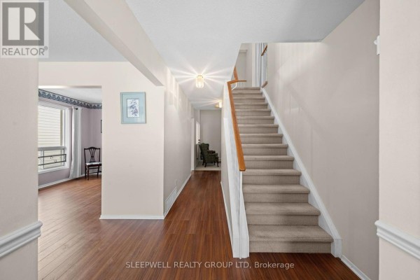 Interior hallway with wood floors and a carpeted staircase leading upstairs. - 31 Tamblyn Crescent, Ottawa