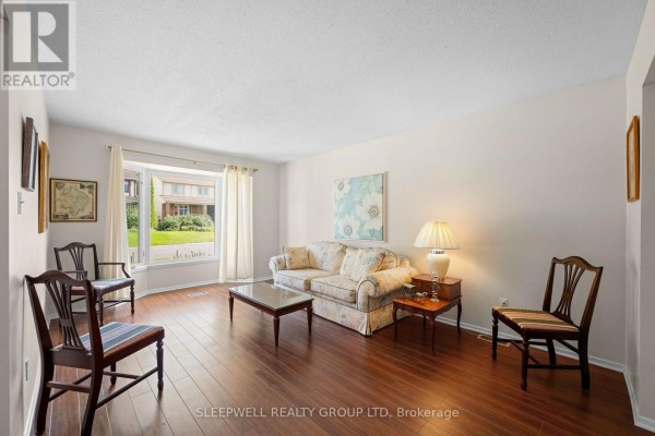 Living room with a bay window, floral sofa, coffee table, and wood floors. - 31 Tamblyn Crescent, Ottawa