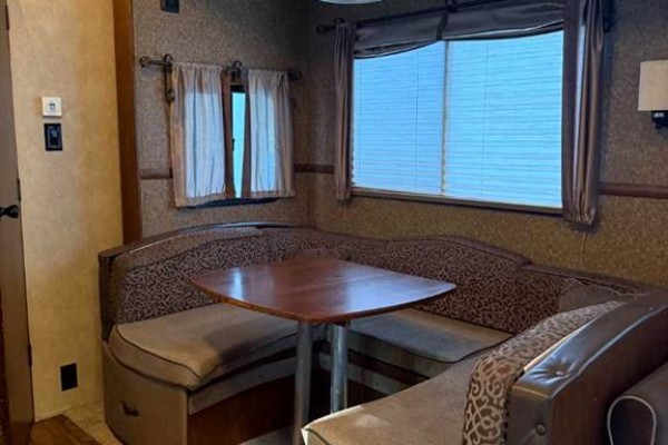 Interior fifth wheel dinette area with U-shaped seating and wooden table. - 31 Timber Drive, 5230 27 Highway, Rural Mountain View County