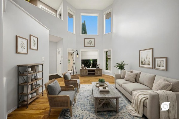 Spacious living room with vaulted ceiling, large bay windows, light gray walls, and hardwood floors. - 31 Treasure Cove, Winnipeg