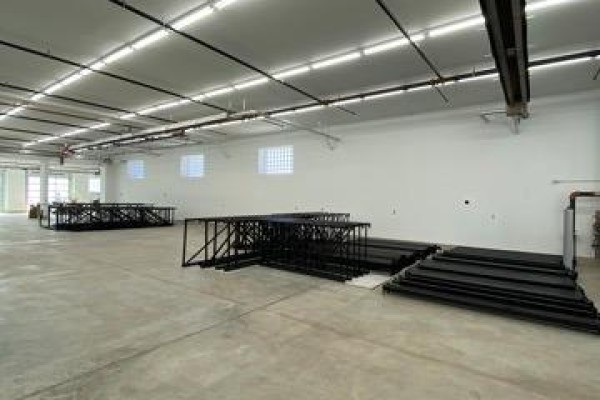 Wide view of an empty commercial interior with white walls, concrete floors, and stacked equipment. - 31 Upton Road, Toronto